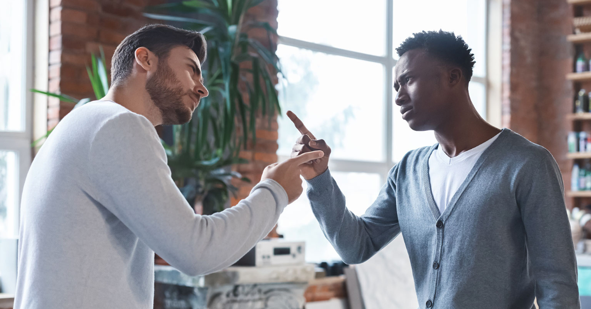 Black and White men argue at work.