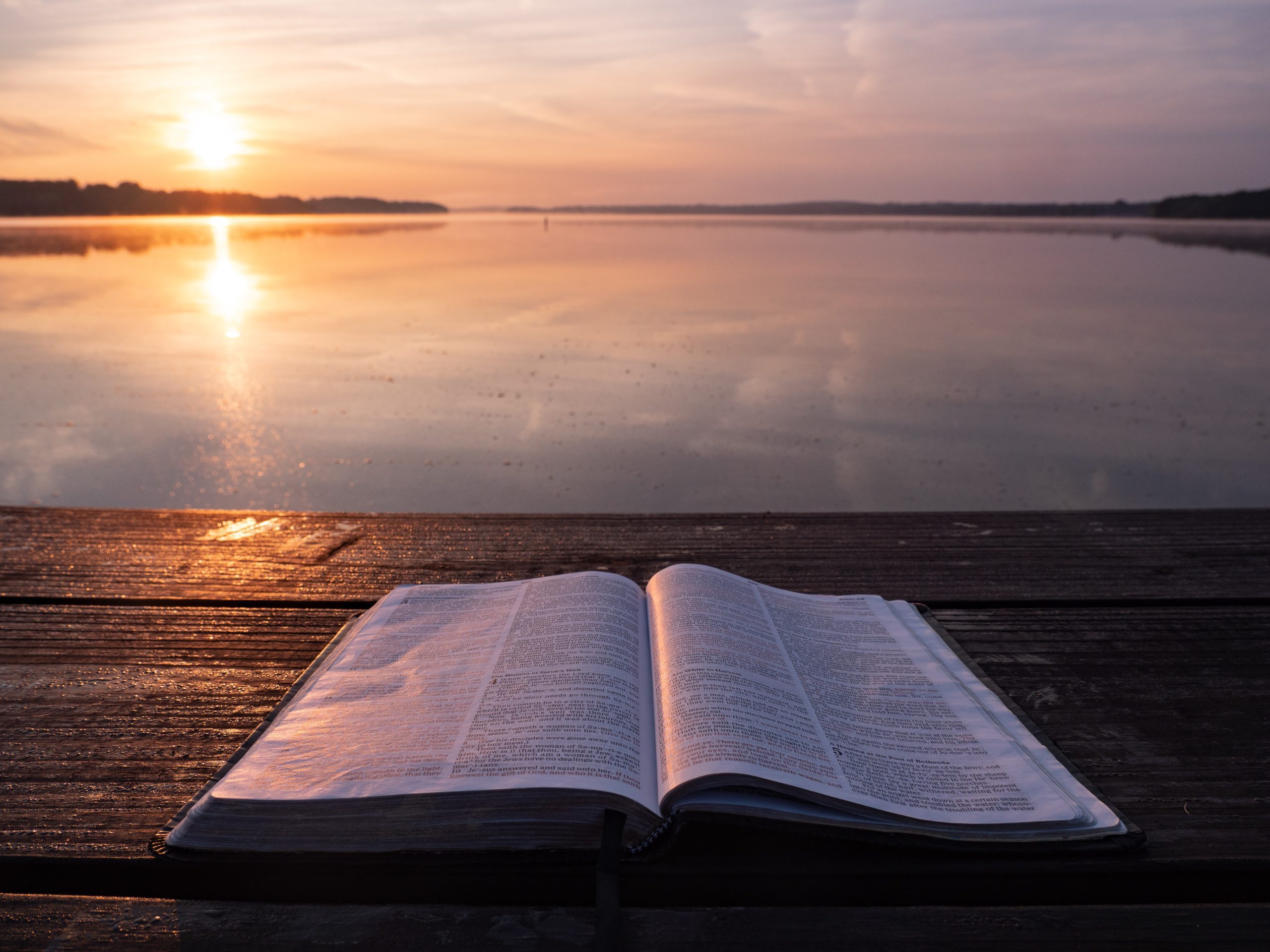 A Bible lies open on a table overlooking a body of water at sunset. God's Word directs us that sometimes just walking away is the right thing to do.