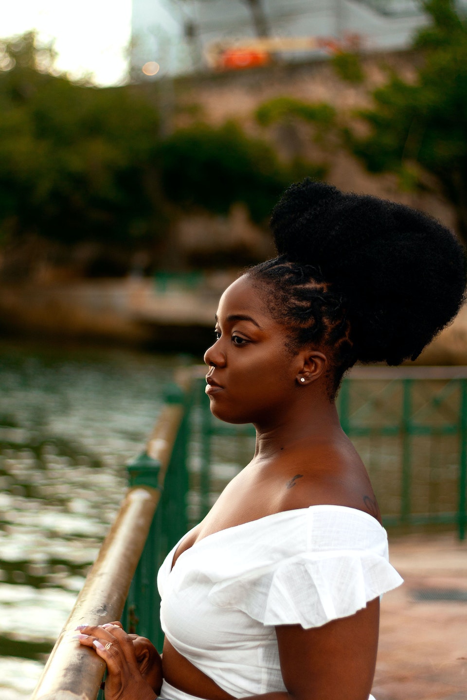 Young Black woman stares out over a river after attending a meeting.